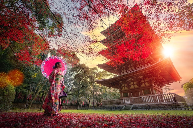 着物の伝統的な衣装で日本人の女の子が公園を散歩します。