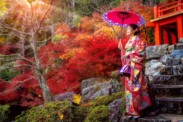 着物の伝統的な衣装で日本人の女の子が公園を散歩します。