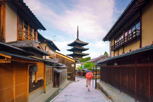 京都の旧市街で赤い傘を持つ浴衣の日本人の女の子