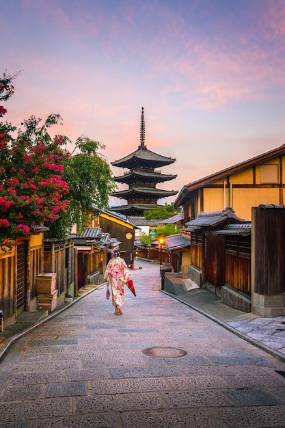 Ragazza giapponese in yukata con ombrellone rosso nella città vecchia di kyoto, giappone