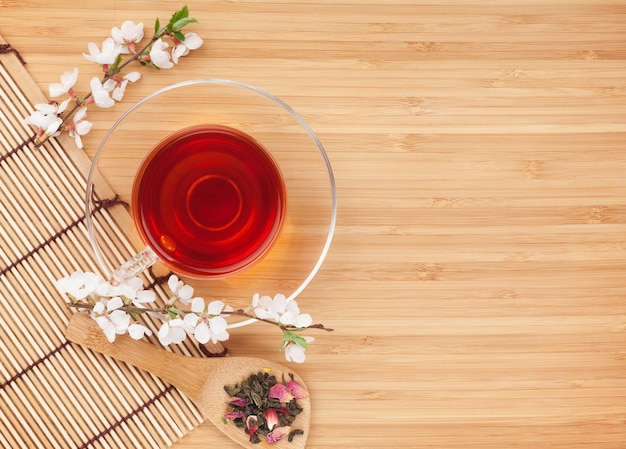 Japanese green tea and sakura branch over mat and bamboo table