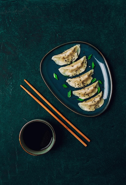 Japanese Gyoza dumplings  with sauce on a green background top view no people tonedboiled