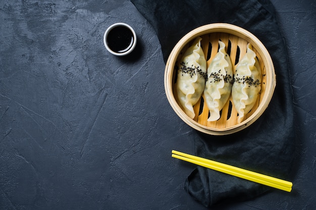 Japanese gyoza in a traditional steamer, yellow chopsticks.  