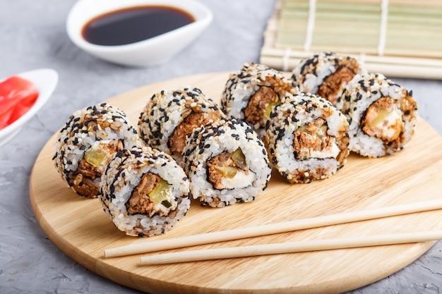 Japanese maki sushi rolls with salmon, sesame, cucumber on wooden board on gray concrete 