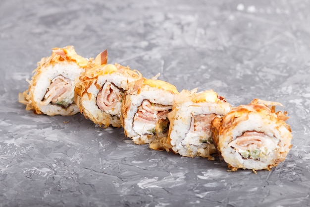 Foto rotoli di sushi giapponesi di maki con tonno, cetriolo, formaggio sulla superficie di calcestruzzo nera. vista laterale.