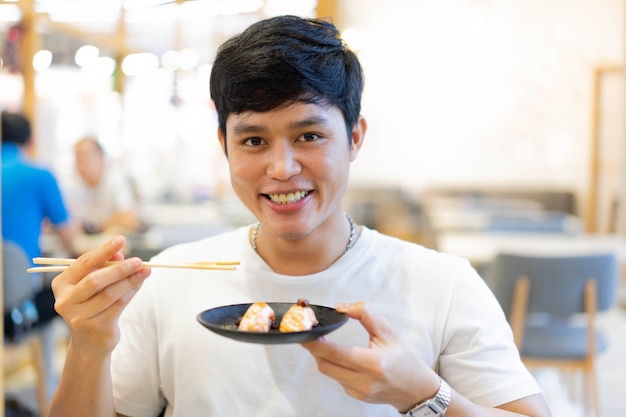 Uomo giapponese tenere piatto di freschezza salmone affettato (sushi) al ristorante