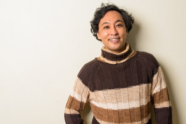 Japanese man with curly hair ready for winter indoors