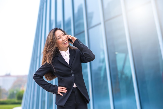 Donna matura giapponese al telefono uomo d'affari si rallegra dei successi raggiunti concetto di uguaglianza e uguaglianza di genere nel mondo del lavoro e della finanza filtro freddo ed effetto luce solare