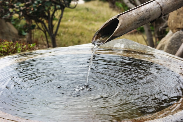 Japanese natural bamboo pipe water flowing into wash place.