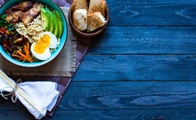 Japanese noodles bowl with chicken, carrots, avocado