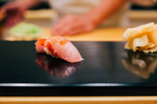 Japanese Omakase in Edo Style Close up Otoro (Fatty Tuna) Sushi served on glossy black plate.