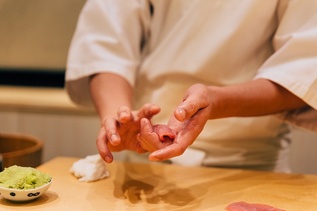 Omakase giapponese che prepara chutoro sushi (medium redty tuna blue) con le mani.