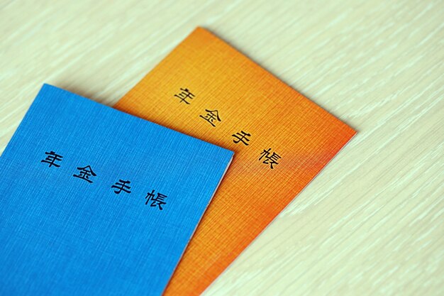Японские пенсионные книжки на столе синяя и оранжевая пенсионная книжка для японских пенсионеров