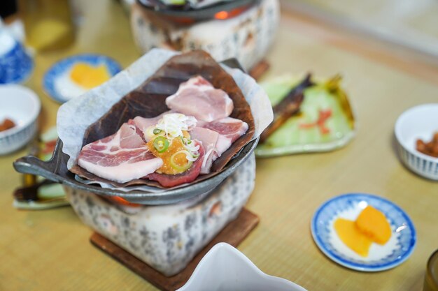 Japanese pork grill style on the traditional stove with local dry leaf and appetizer around