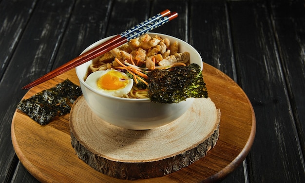 Foto zuppa di ramen giapponese con pollo, uova, aglio e tagliatelle su uno sfondo di legno scuro. tagliatelle asiatiche di miso ramen.