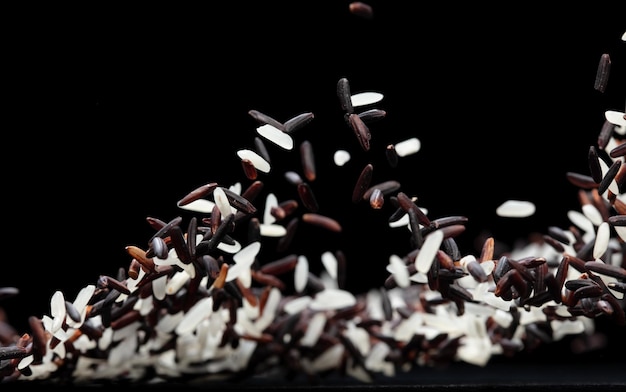 Photo japanese riceberry flying explosion white grain rices berry fall abstract fly beautiful complete seed jasmine riceberry splash in air food object black background isolated selective focus blur