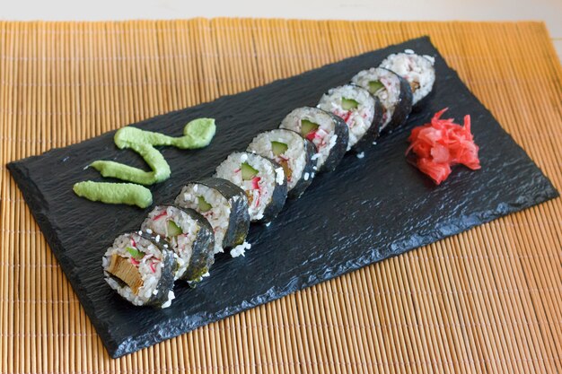 Japanese rolls with cucumber, crabs and omelet on a black board with wasabi and ginger