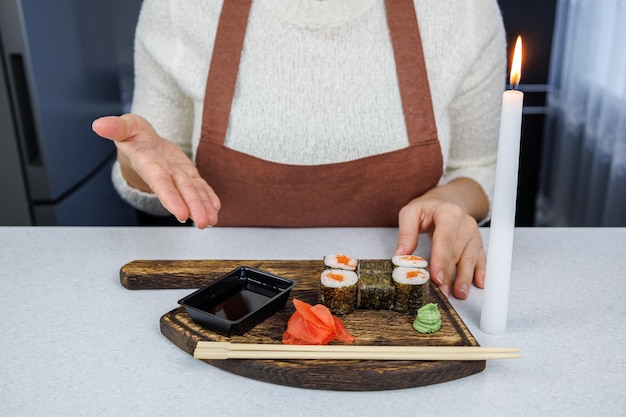 Japanese rolls with red fish in an open cardboard box Girl eating sushi with chopsticks Table decoration