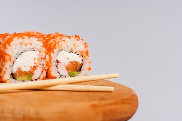 Japanese rolls with rice and salmon on a wooden board on a gray wall