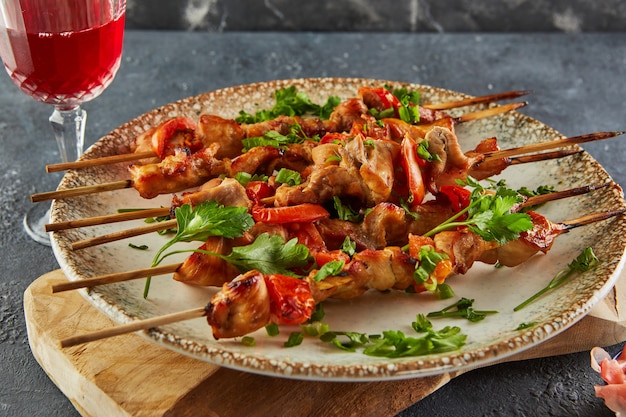 Japanese style yakitori shashlik on a wooden board with a glass of red wine and ginger