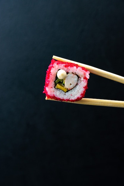 Japanese sushi in red flying fish roe tobiko caviar isolated on dark