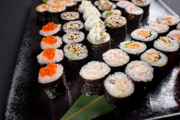 Japanese sushi rolls set served on black plate on dark background