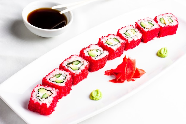 Japanese sushi rolls with avocado in red caviar of flying fish on white plate