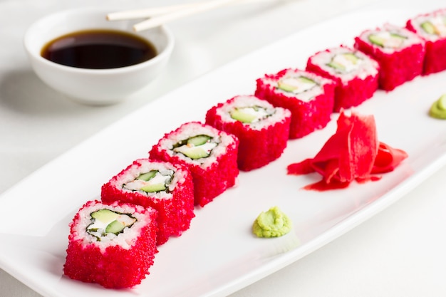 Японские суши-роллы с авокадо в красной икре летающей рыбы на белой тарелке