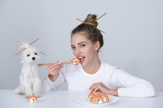 写真 日本の寿司スタイルセクシーな女性は日本の伝統的な食べ物の巻き寿司を食べる女の子は箸で日本の寿司ロールフィラデルフィアを持っています犬のペットとの広告