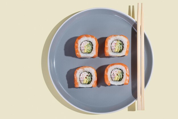 Japanese sushi with salmon dragon rolls on a bright yellow background Pop art Tasty snacks on a gray plate and chopsticks