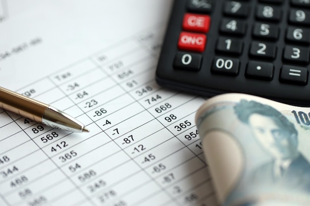 Photo japanese tax calculations lies on table with calculator pen and japanese yen money bills close up