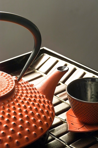 テキストアジア文化のためのテーブルライフスタイルスペース上の日本のティーポットとオレンジ色の鉄のカップ