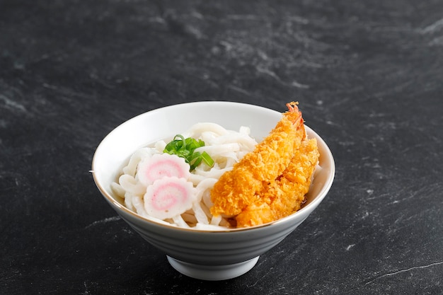 Japanese Tempura Udon Noodles on White Bowl over Black Marble Table