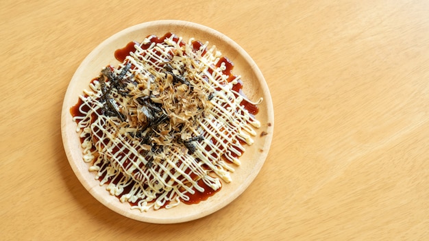 Pancake tradizionali giapponesi (okonomiyaki) su una tavola di legno.