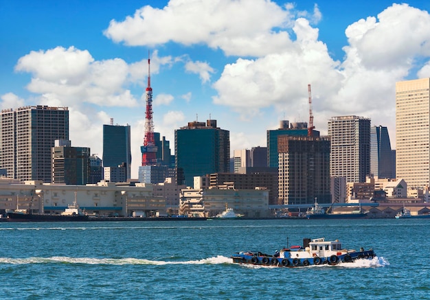 Japanese tugboats sailing in front of the hinode pier on tokyo port with tokyo tower