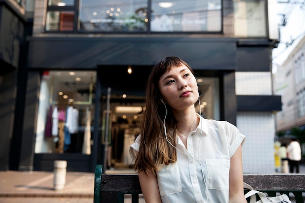 Japanese woman on a bench wearing earphones listening to music