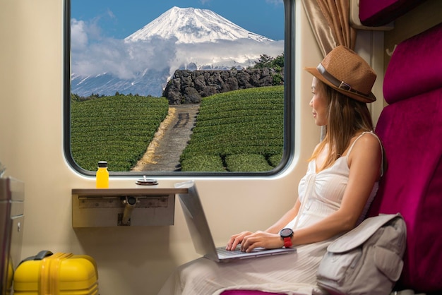 Japanese woman in green tea field with Fuji mountain and red umbella