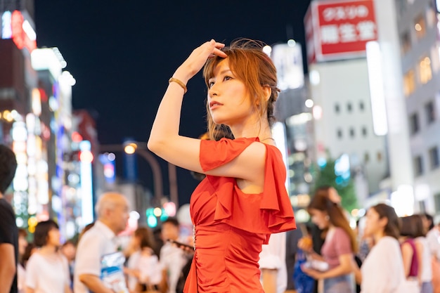 日本の女性が東京の通りで華やかな赤いドレスでポーズ
