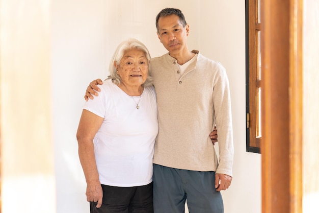 写真 日本生まれの母と息子が笑顔でカメラを見ながら抱きしめて立っています