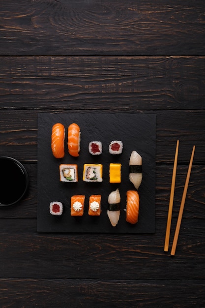 Japans eten restaurant, sushi en broodjes op donkere achtergrond. Set met stokjes en sojasaus. Bovenaanzicht op zwart hout