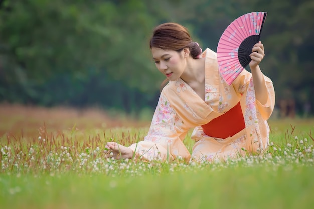 Japans meisje dat in traditionele kleren op het park zit