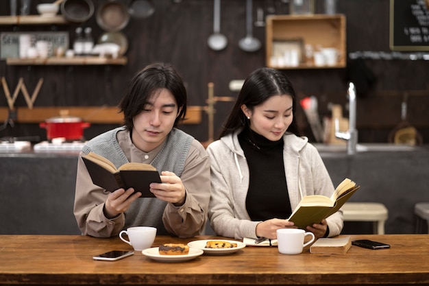 Foto japans stel dat koffie drinkt en leest uit notitieboekjes in een restaurant