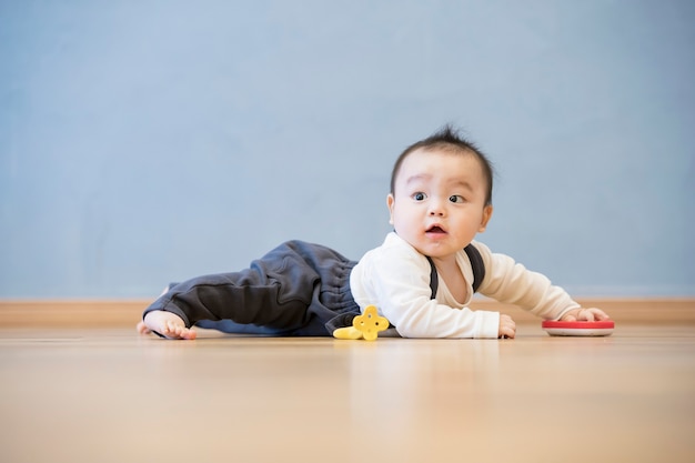 Japanse baby kruipen op de houten vloer in de kamer