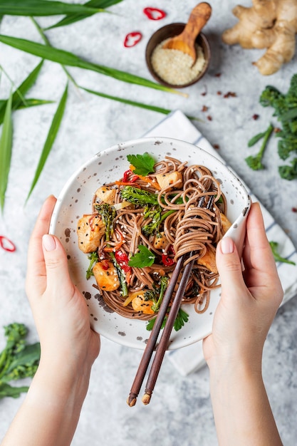 Japanse boekweitnoedels Yakisoba met kip en groenten op een lichte achtergrond