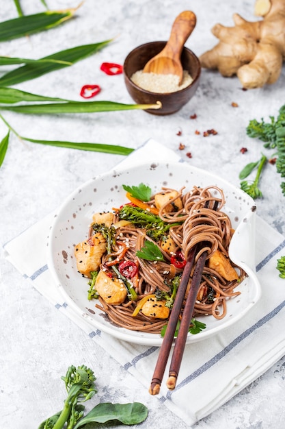 Japanse boekweitnoedels Yakisoba met kip en groenten op een lichte achtergrond