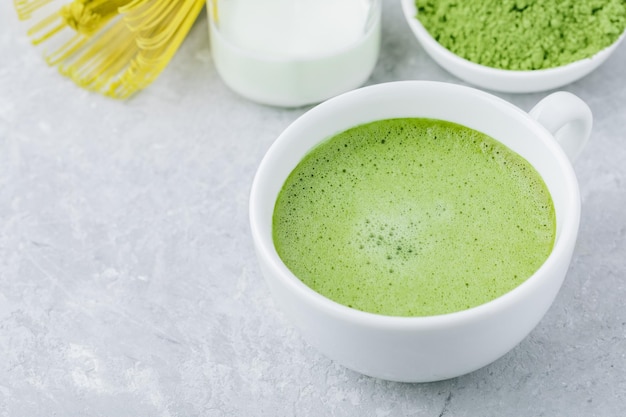 Japanse matcha groene thee latte in witte kop op grijze steenachtergrond