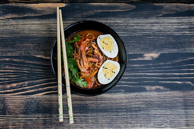 Japanse ramen met zeevruchten, kruiden en ingelegde eieren op een donker oppervlak