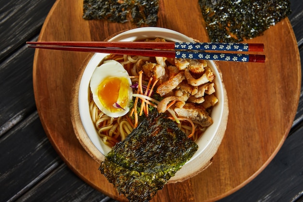 Foto japanse ramen soep met kip, ei, knoflook en noedels op een donkere houten