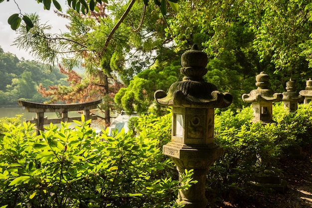 Japanse stenen lantaarns in een tempeltuin, groene vegetatie rond.