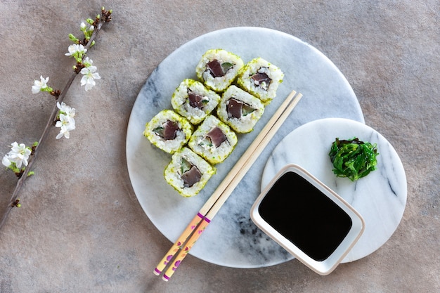 Japanse sushi geserveerd met bloeiende takken van de lentekersen. Bovenaanzicht, close-up op lichte achtergrond.